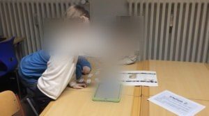 Drei Schüler:innen beschreiben mit Hilfe von Legekarten eine ausgedruckte Internetseite.