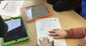 Drei Schüler:innen beantworten mit Hilfe von Tablets einen Arbeitsbogen.