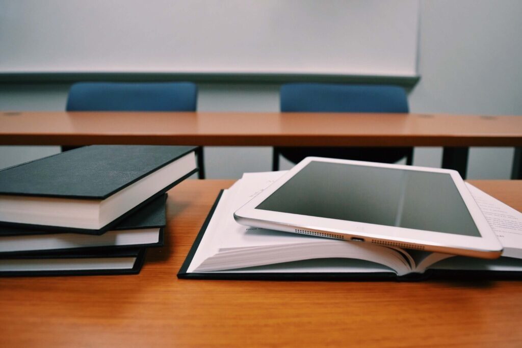 Bücher sowie Tablet liegen auf dem Tisch.