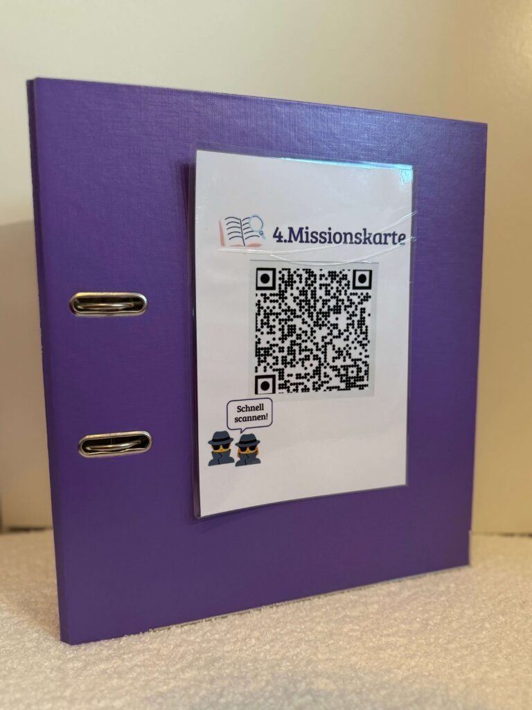 Der lila-farbige Ordner mit der aufgeklebten Missionskarte als QR-Code