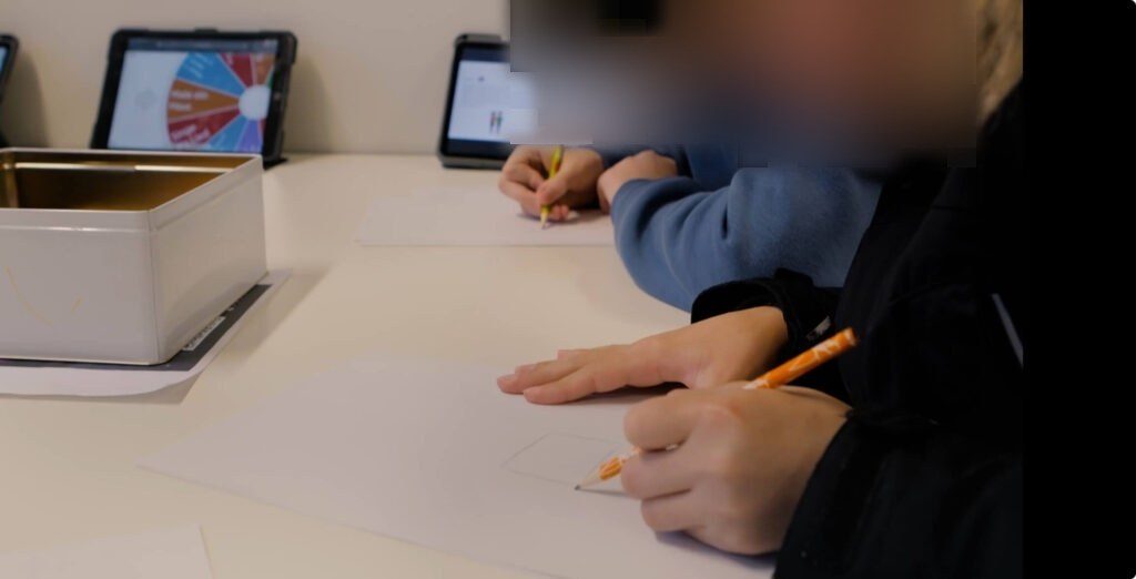 Zwei Schüler sind das Team Mensch und malen auf einem Blatt ein Haus.