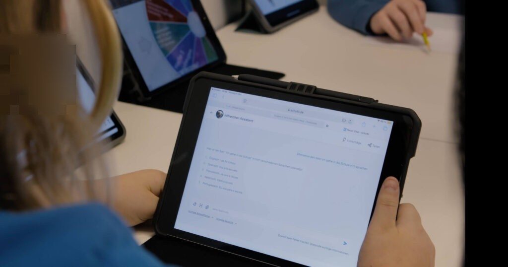 Eine Schüler liest auf ihren iPad die Ergebnisse der SchulKI zu der Aufgabe "Übersetze folgenden Satz in 5 Sprachen: Ich gehe in die Schule".