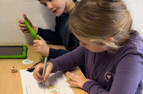Ein Jungen und ein Mädchen sitzen an einem Tisch und erarbeiten mit einem iPad und einer Mind Map ihr Märchen.